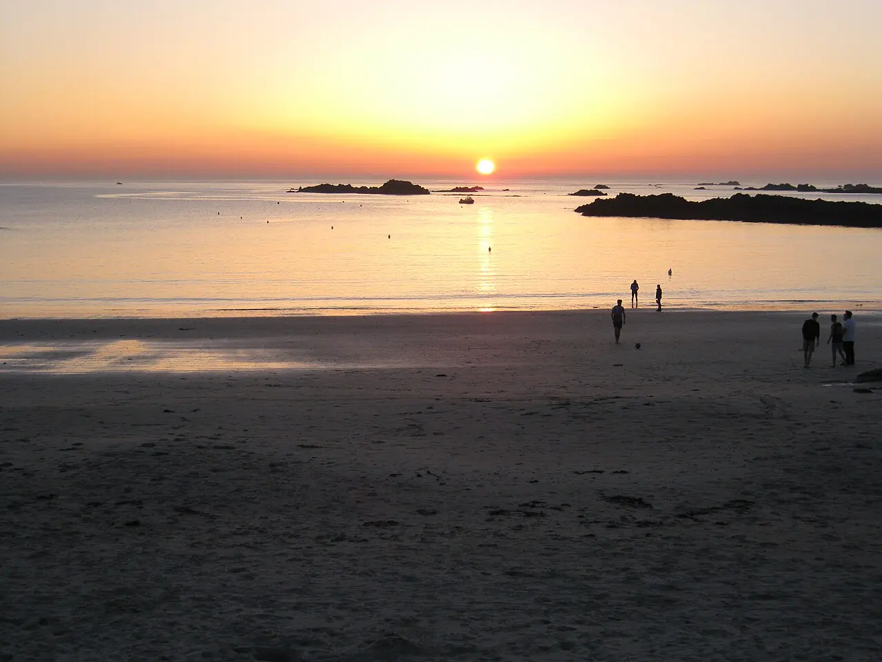 Sunset over the sand and rocky edges of Cobo Bay, Guernsey.
