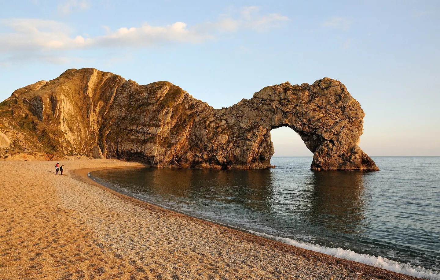 The limestone arch and beach at Durdle Door in warm evening light