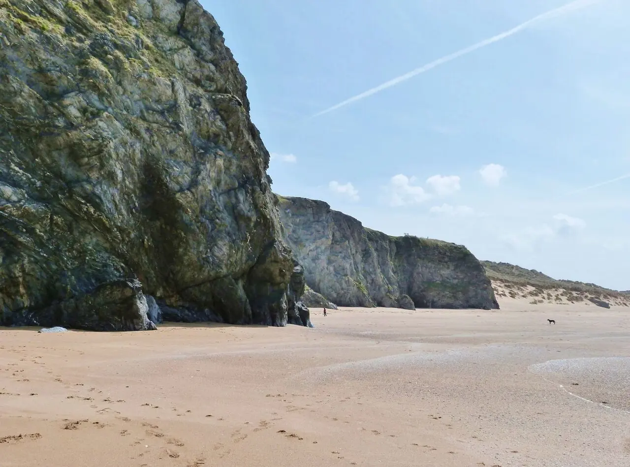 A lone dog walker on the beach at Holywell Bay, Cornwall
