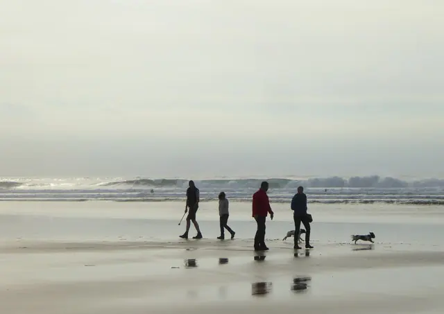 Dog walkers on the beach at Mawgan Porth