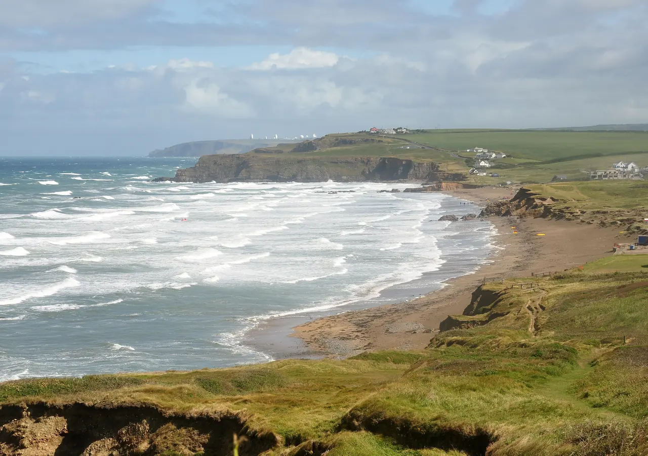 View north across Widemouth Bay, near Bude in Cornwall, with the satellite dishes of GCHQ Bude visible in the distance.