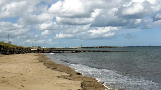 Cambois beach - view north. In the distance (centre, left), the sun is picking out the white caravans of 69595 with the eight chimneys of 298850 to their left and the single tall.